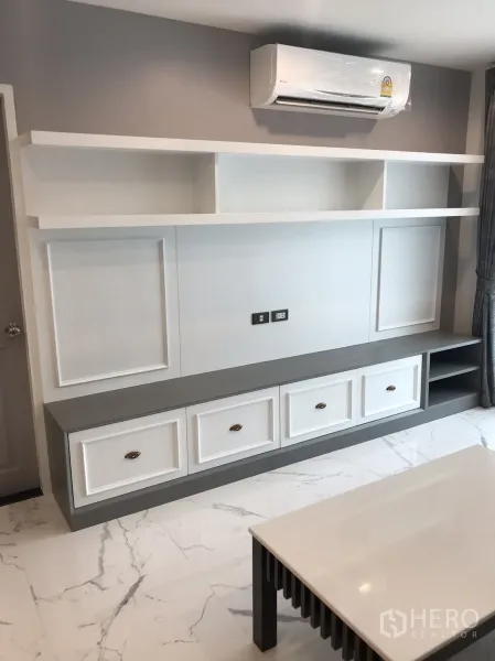 Condominium for rent or sale in Khlong Toei, Bangkok - Close-up of white built-in media wall with overhead shelving and air conditioner.