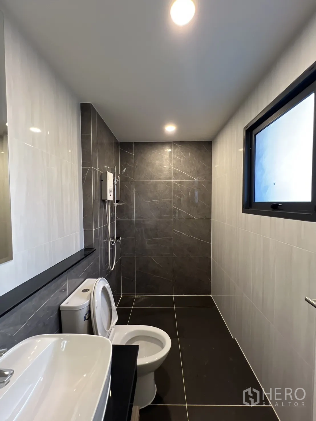 Detached House for rent or sale in Bang Phli, Samut Prakan - Modern bathroom with dark tiles, walk-in shower and window.