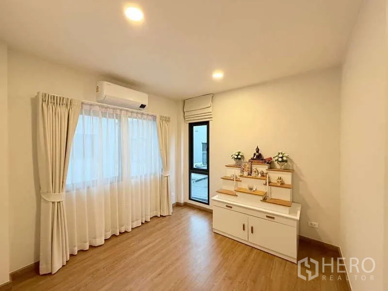 Detached House for sale in Bang Phli, Samut Prakan - Bright multi-purpose room with wood flooring, air conditioner and large curtained window.