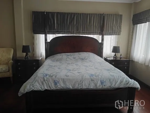Detached House for rent in Huai Khwang, Bangkok - Master bedroom with dark wood bed frame and bedside tables