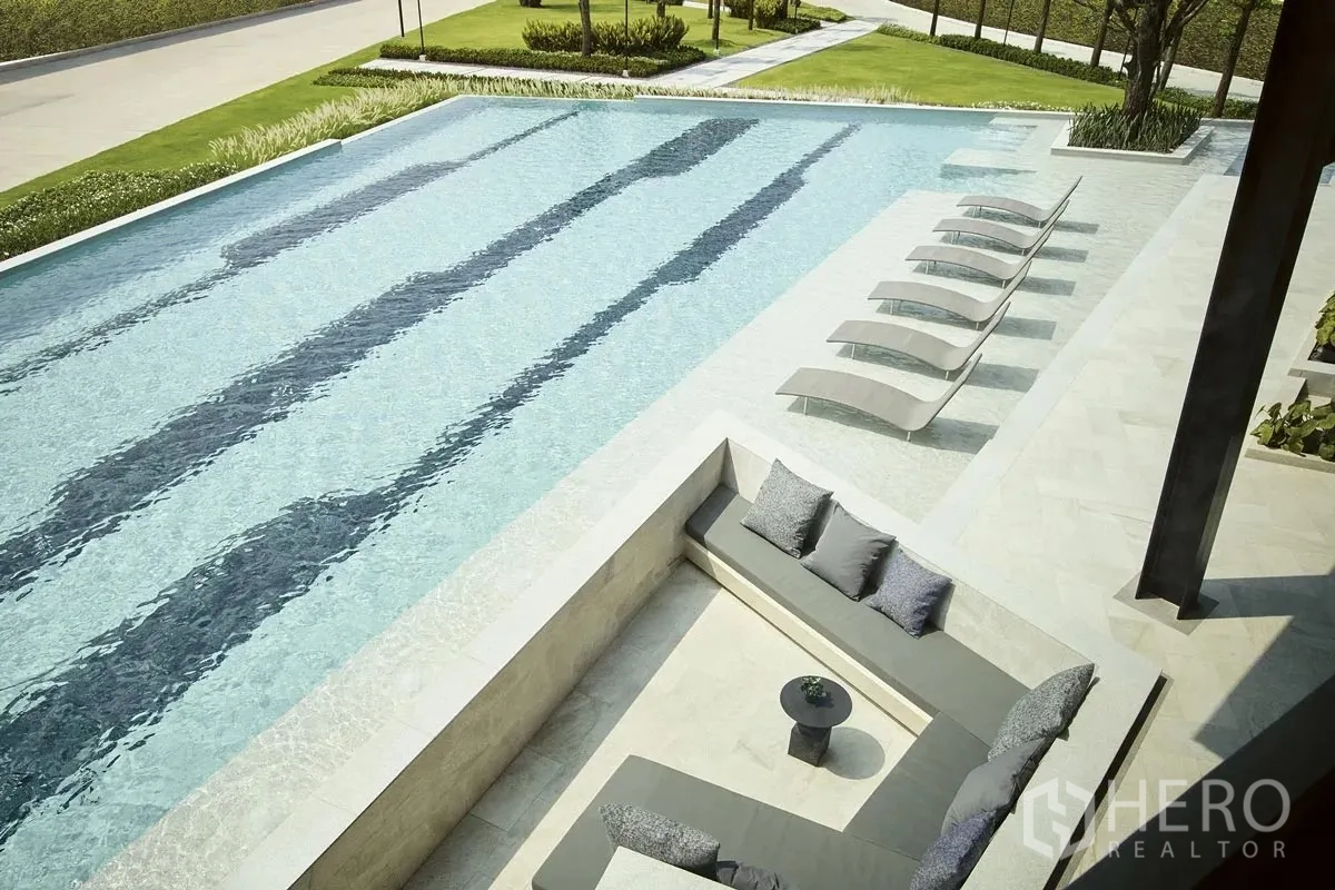 Detached House for rent or sale in Pathum Thani - Aerial view of a large swimming pool with shaded seating areas.