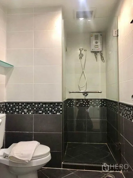 Condominium for rent in Khlong Toei, Bangkok - Second bathroom with glass shower, water heater and mosaic tiles.