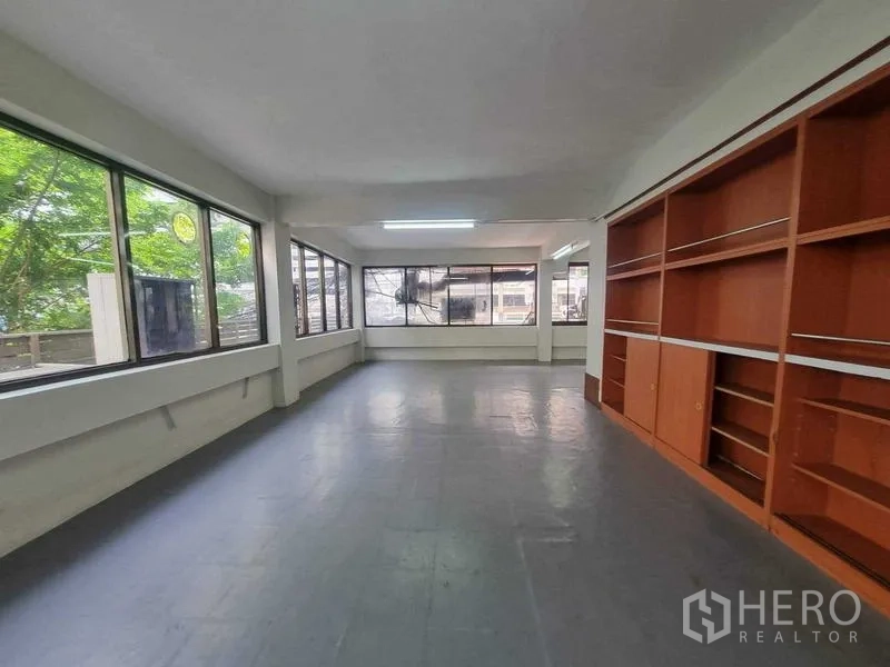 Retail Space for rent in Bang Rak, Bangkok - Upper-floor workspace with wraparound windows, built-in shelving and leafy views.