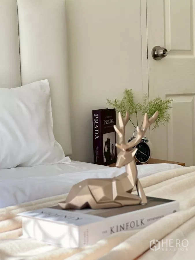 Detached House for rent in Huai Khwang, Bangkok - Bedside vignette with decorative deer statue on design books next to an alarm clock.