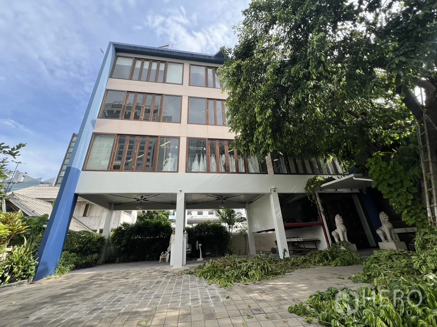 Home Office for rent in Watthana, Bangkok - Four-storey home office exterior with covered stilt parking, large wood-framed windows and leafy trees in a quiet lane.