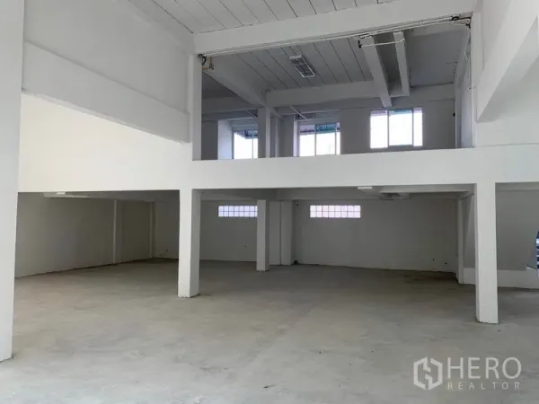 办公空间 出租在Huai Khwang, Bangkok - 挑高大厅带夹层，混凝土地面与结构柱，空间开阔。