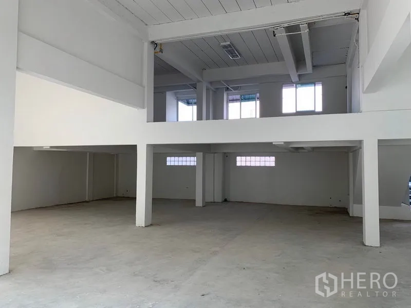 办公空间 出租在Huai Khwang, Bangkok - 挑高大厅带夹层，混凝土地面与结构柱，空间开阔。