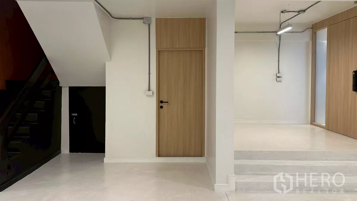 带办公室的家 出租在Watthana, Bangkok - 一层入口大厅，木门、外露管线与楼梯下收纳。