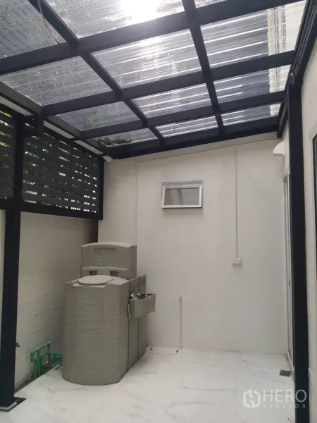 Townhouse for rent in Khlong Toei, Bangkok - Covered rear utility terrace with a transparent roof, water tank and wall-mounted sink.