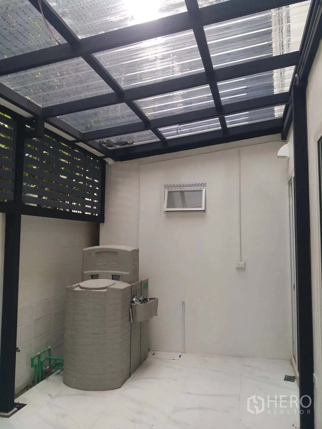 Townhouse for rent in Khlong Toei, Bangkok - Covered rear utility terrace with a transparent roof, water tank and wall-mounted sink.
