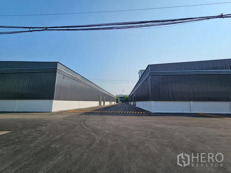 Warehouse for rent in Khlong Toei, Bangkok - Two parallel warehouse buildings flanking a central access road and striped loading area.