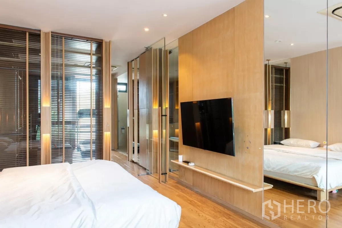 Townhouse for rent in Lat Phrao, Bangkok - Master bedroom view with wall-mounted TV, glass partitions and warm lighting.