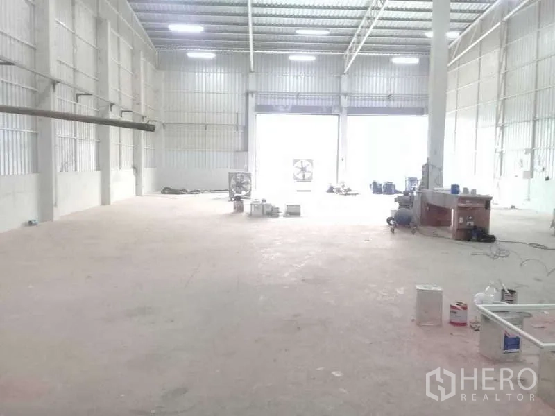 货栈 出租在Khlong Luang, Pathum Thani - 仓库内部采光明亮，钢结构高层高、混凝土地面，远端大型卷闸门便于卡车装卸。
