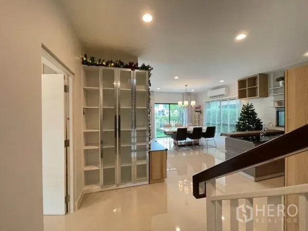 Detached House for sale in Pak Kret, Nonthaburi - Open-plan dining and kitchen with glossy floors, glass cabinets and sliding doors to the garden.