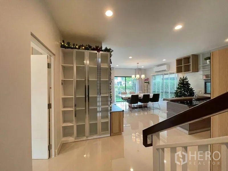 Detached House for sale in Pak Kret, Nonthaburi - Open-plan dining and kitchen with glossy floors, glass cabinets and sliding doors to the garden.