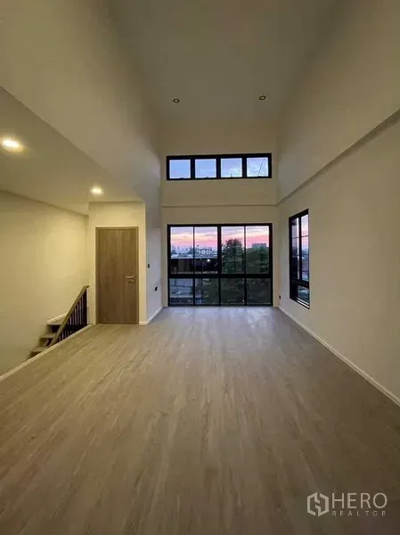 Home Office for sale in Lat Phrao, Bangkok - Spacious upper-floor room with wide glass doors and sunset view.