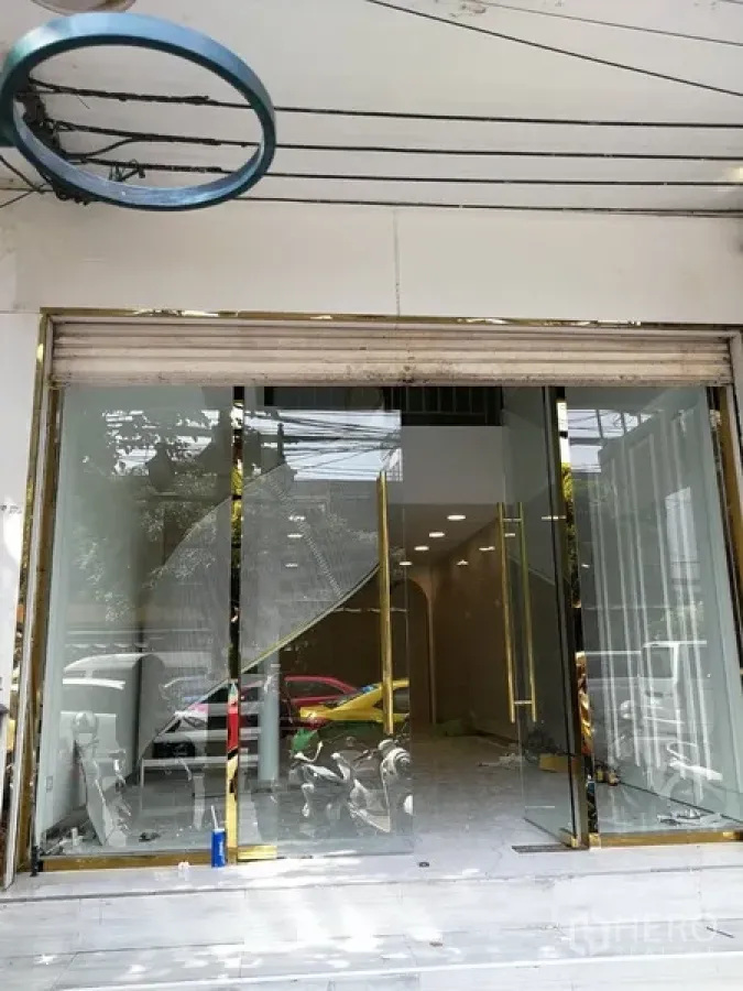 Shophouse for rent in Watthana, Bangkok - Street-facing shophouse facade with full-height glass doors, gold trim and rolling shutter in Thonglor area.
