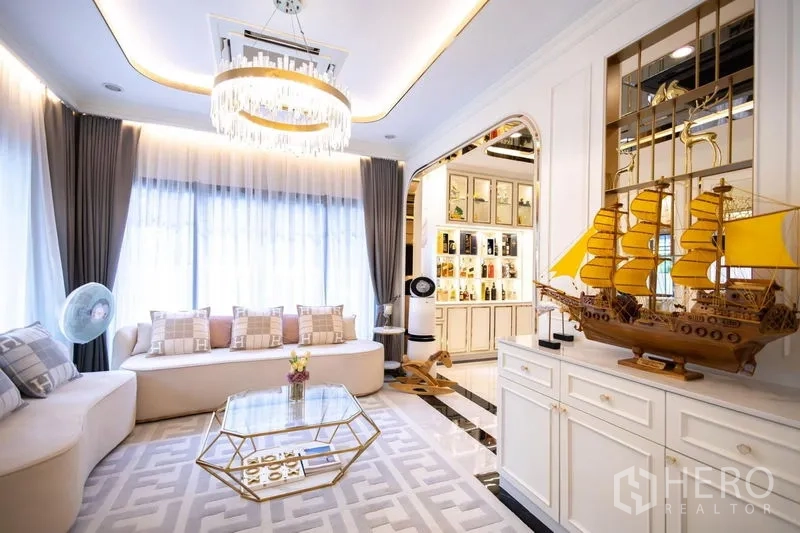บ้าน ขายในPak Kret, Nonthaburi - ห้องรับแขกดีไซน์หรู โซฟาโค้ง โคมระย้า และหน้าต่างบานใหญ่