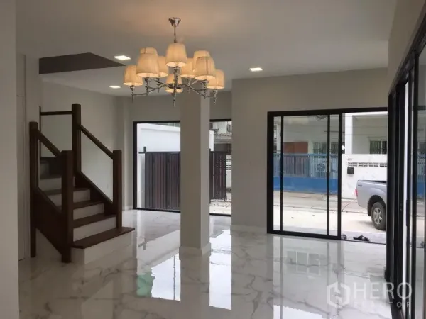 Detached House for rent in Khlong Toei, Bangkok - Bright ground floor living area with marble-look tiles, sliding doors and a wooden staircase