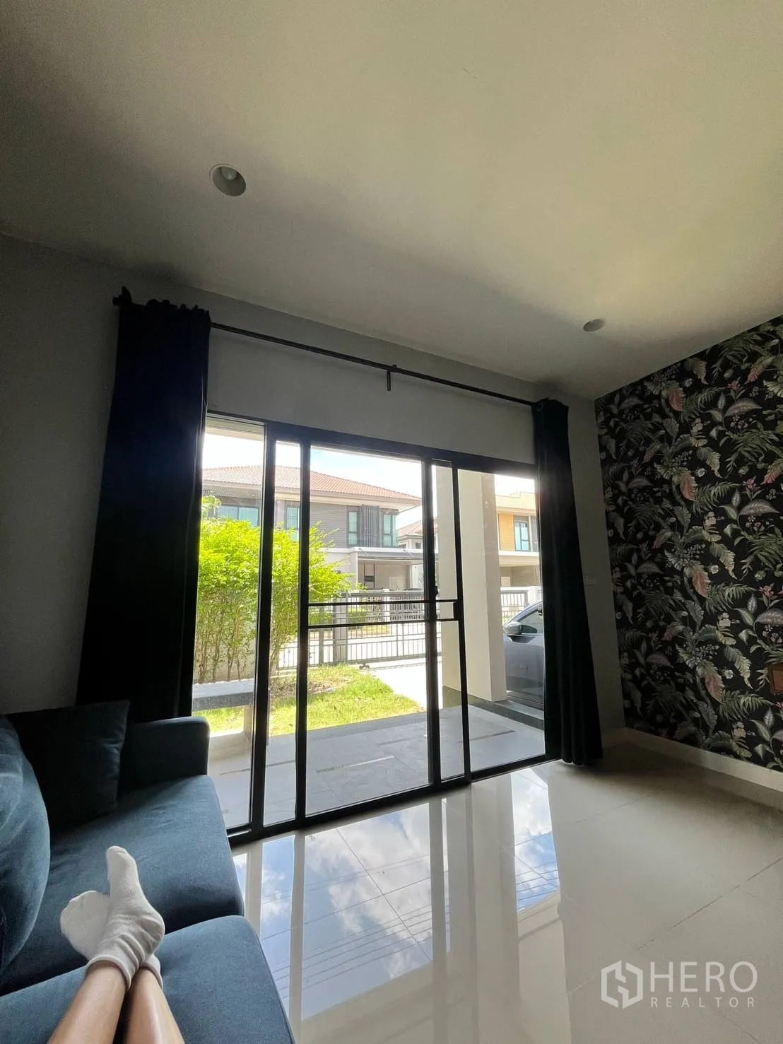 Detached House for rent or sale in Lam Luk Ka, Pathum Thani - Living area looking to garden through sliding doors and a feature wallpaper wall.
