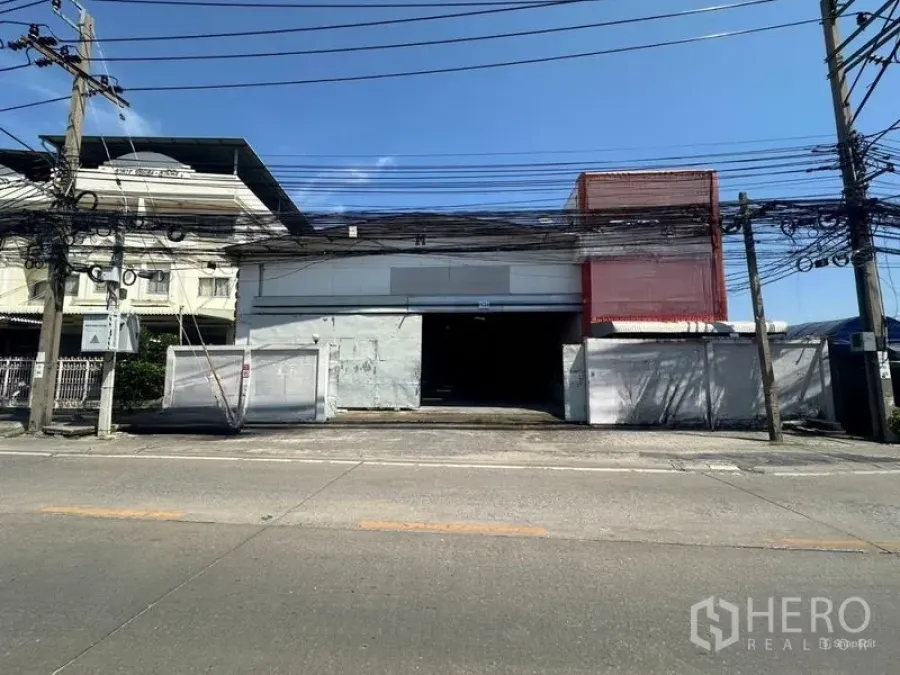 Warehouse for rent in Suan Luang, Bangkok - Warehouse facade with gated driveway and wide entrance viewed from the street.