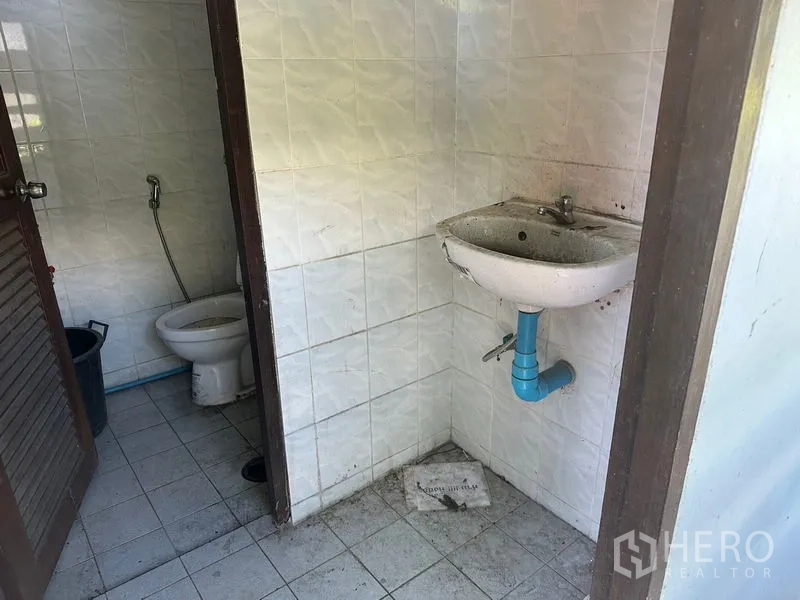 货栈 出租在Suan Luang, Bangkok - 园区内员工卫生间，瓷砖地面，配坐便与壁挂洗手盆。