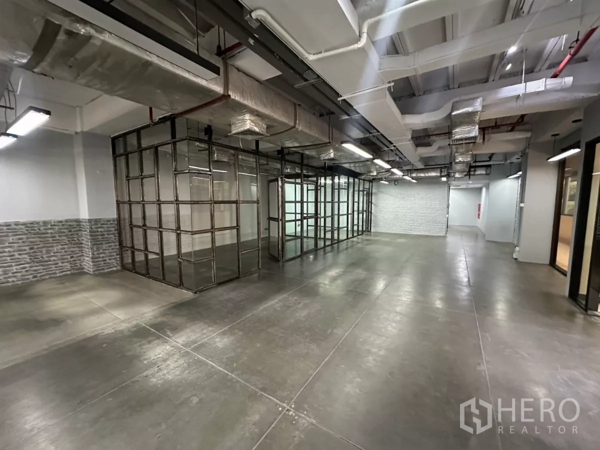 Office Space for rent - Wide view of fitted office floor with polished concrete and glass rooms.