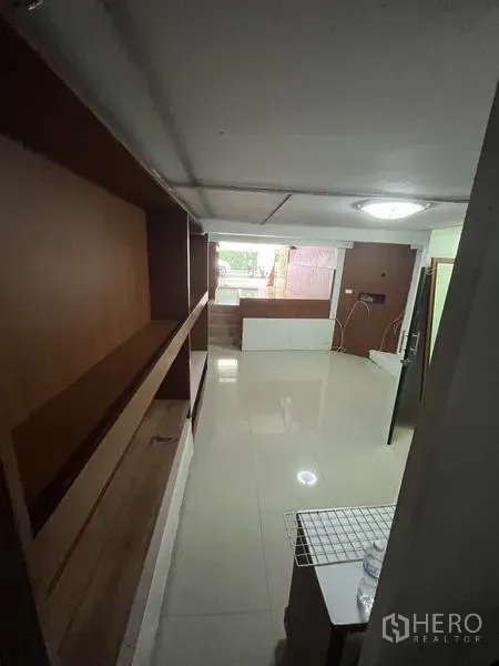 店屋 for rent in Khlong Toei, Bangkok - 长形走道空间，墙面木质层架与地砖地面。