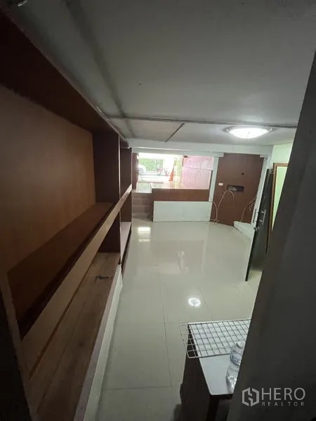 店屋 for rent in Khlong Toei, Bangkok - 长形走道空间，墙面木质层架与地砖地面。