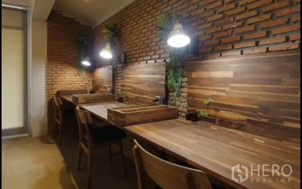 Home Office for rent in Khlong Toei, Bangkok - Row of wooden study desks along an exposed brick wall with task lamps and small plants.
