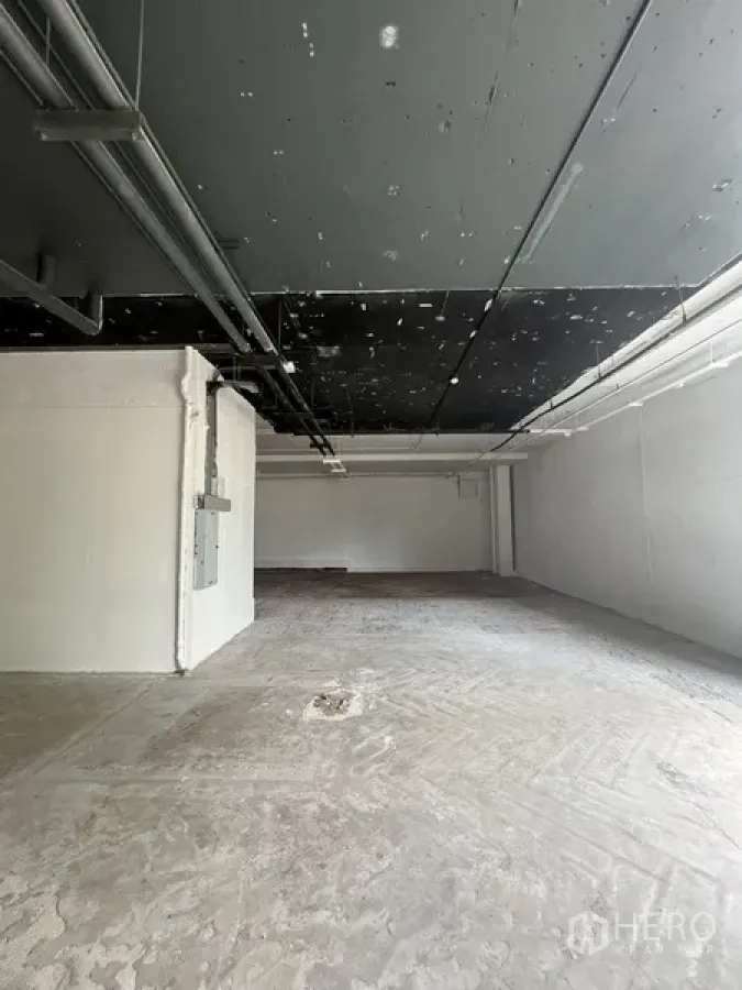 Retail Space for rent - Bare-shell retail unit with exposed black ceiling, concrete floor, and white walls ready for tenant fit-out.