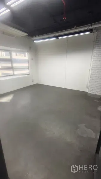 Office Space for rent in Pathum Wan, Bangkok - Corner office room with concrete floor, white brick accent wall and window for natural light.