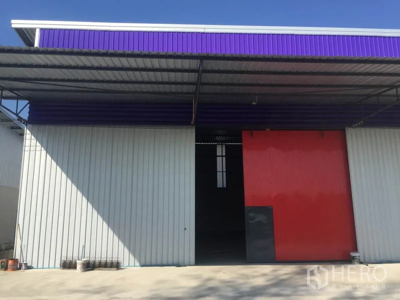 Warehouse for rent in Sai Mai, Bangkok - Warehouse exterior in Sai Mai with purple fascia, large red sliding door and wide concrete forecourt.