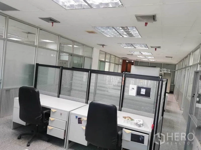 Office Space for rent in Bang Na, Bangkok - Workstations with divider screens, swivel chairs, and overhead fluorescent lighting in a glass-partitioned office.