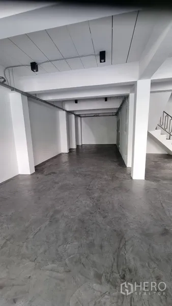 Shophouse for rent in Khlong Toei, Bangkok - Long open hall with white beams and smooth concrete floor suitable for showroom use.