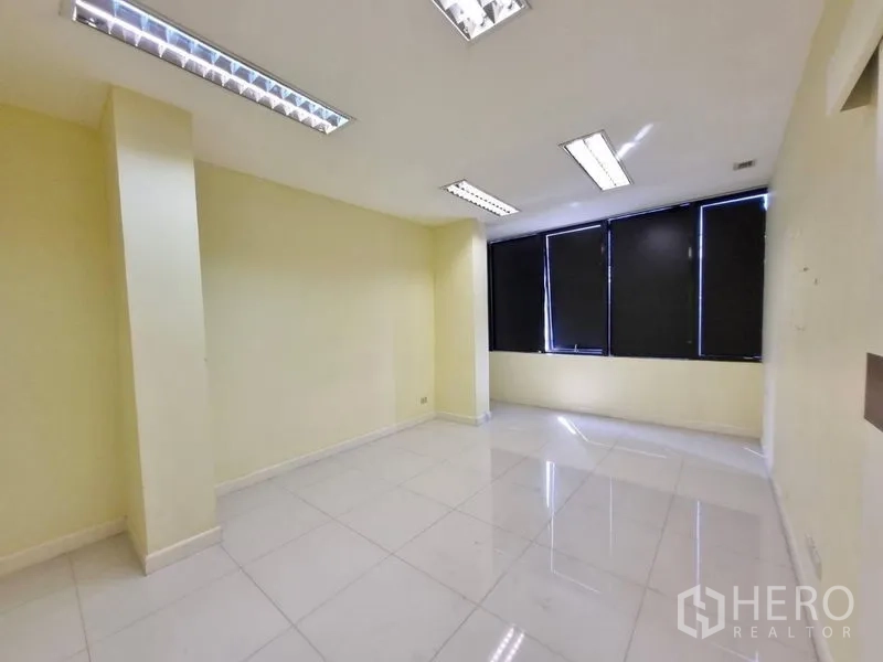 Shophouse for rent in Watthana, Bangkok - Bright office room with fluorescent lighting and black window blinds.