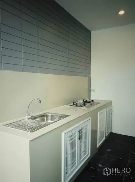 Townhouse for rent in Suan Luang, Bangkok - Linear kitchen with sink, gas cooktop and tiled backsplash.