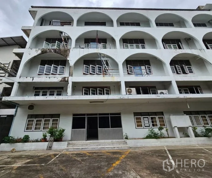 Factory for rent in Bang Kho Laem, Bangkok - Four-storey factory office facade with arched balconies and windows.