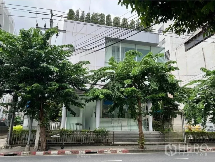 办公空间 出租在Bang Rak, Bangkok - 曼谷邦拉区现代低层办公楼，玻璃外立面与街道绿树。