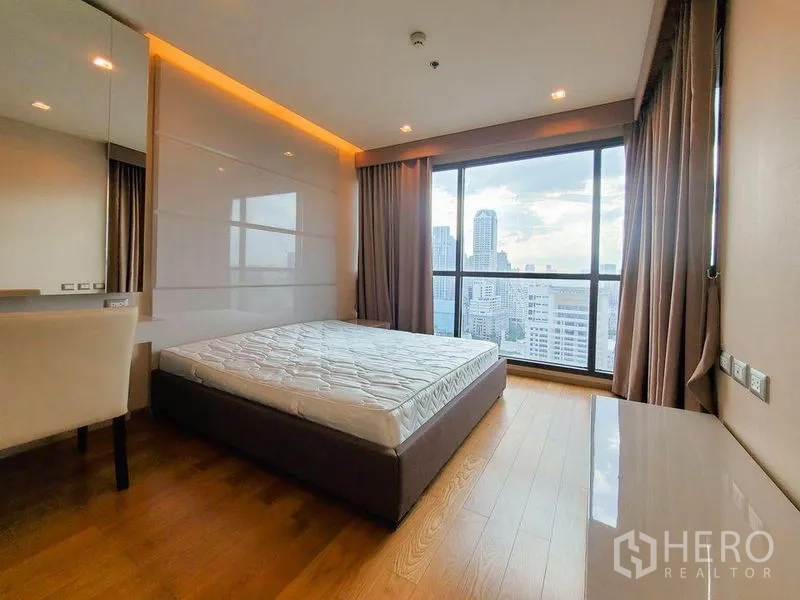 Condominium for rent in Bang Rak, Bangkok - Bright high-floor bedroom with floor-to-ceiling window, warm wood floors, and panoramic city skyline view.