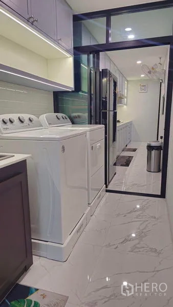 Detached House for sale in Sai Mai, Bangkok - Laundry room with washer and dryer beside a sliding glass door leading to the kitchen.