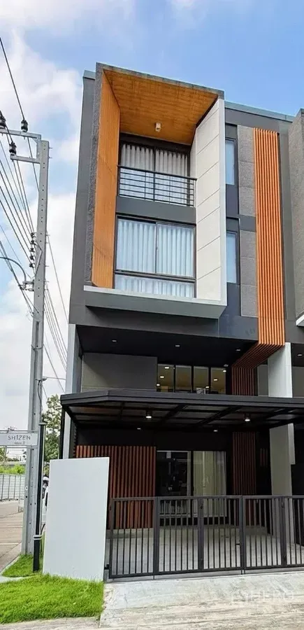 Townhouse for rent in Suan Luang, Bangkok - Modern 3.5-storey corner townhouse facade with covered parking and vertical wood slats.