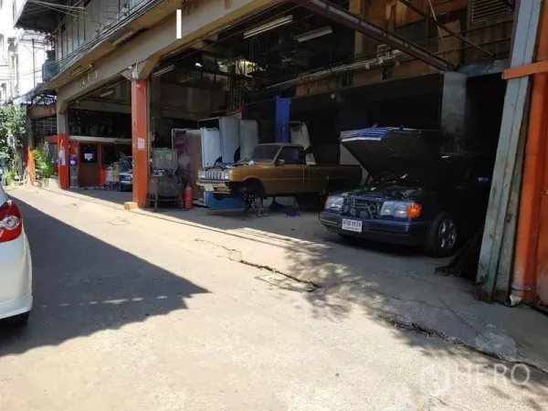 Warehouse for rent in Yan Nawa, Bangkok - Street-facing warehouse bays with cars being serviced and wide entrances for loading.