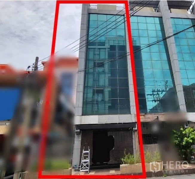 Shophouse for rent in Khlong Toei, Bangkok - Street-facing glass facade of a multi-storey shophouse highlighted within a red outline.