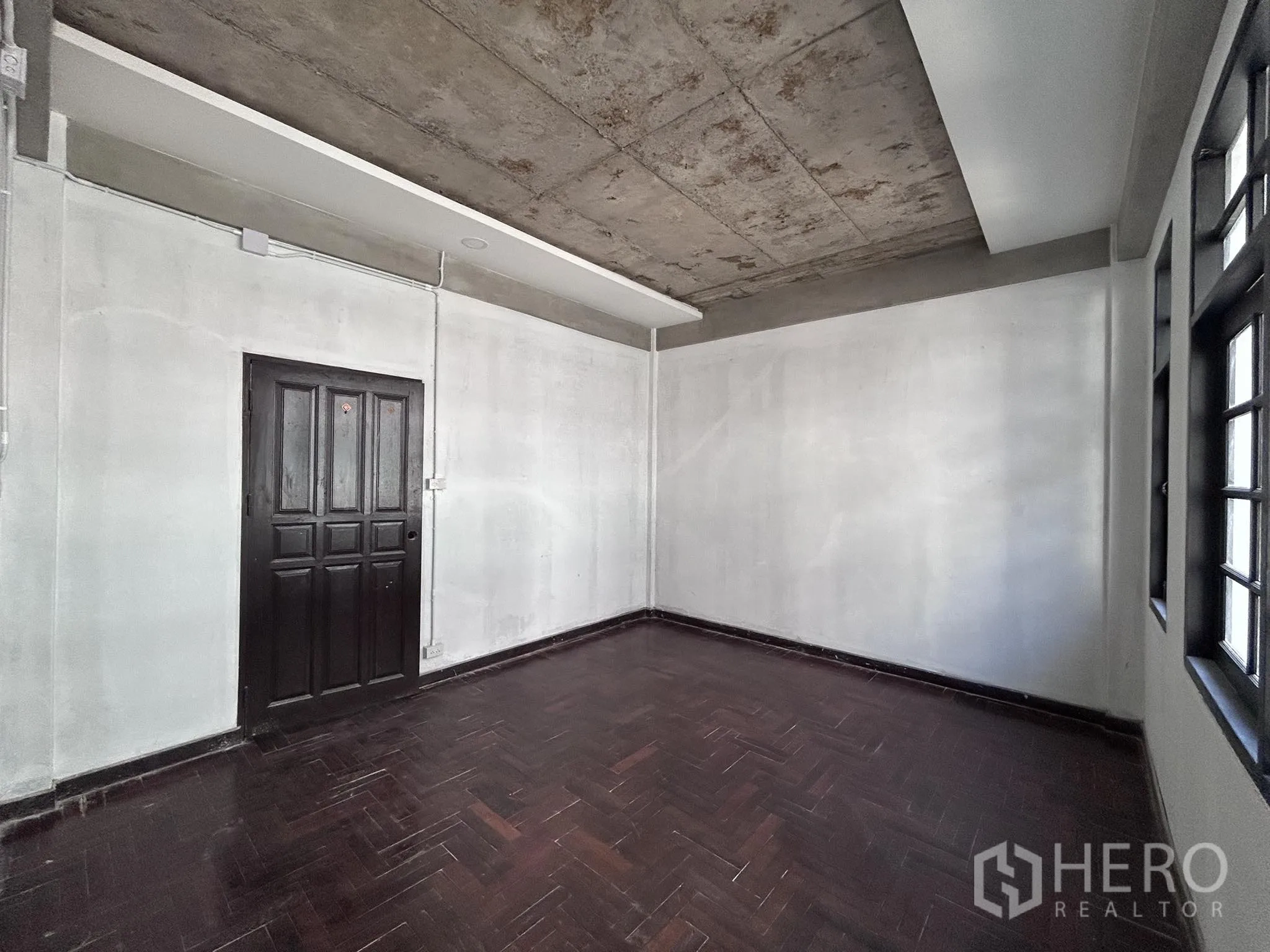 Home Office for rent or sale in Watthana, Bangkok - Room with dark herringbone wood floor, windows and solid door.
