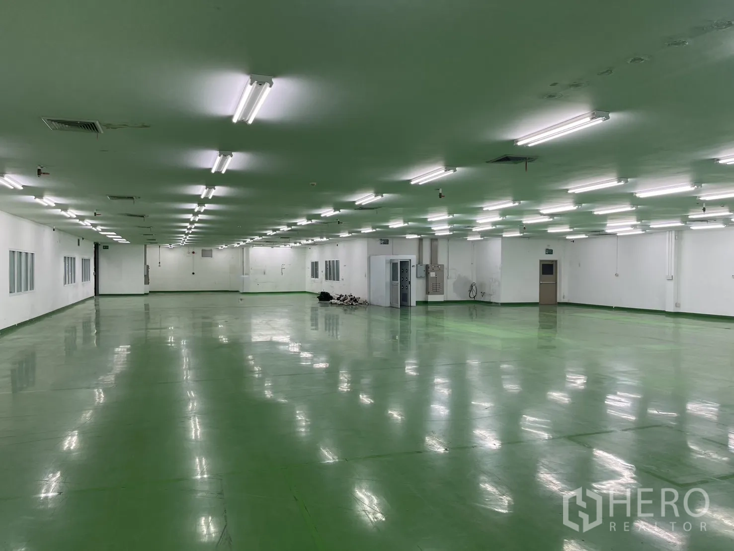 Factory for rent in Mueang Samut Prakan, Samut Prakan - Clean factory interior with interior windows, access doors, and power cabinets along the wall.
