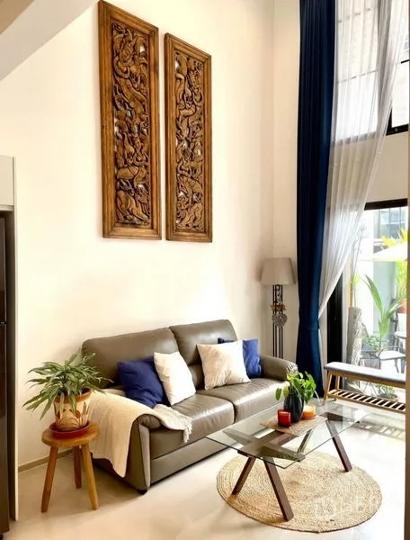 Townhouse for rent in Suan Luang, Bangkok - Bright living room with high ceiling, leather sofa, glass coffee table, and tall curtains.