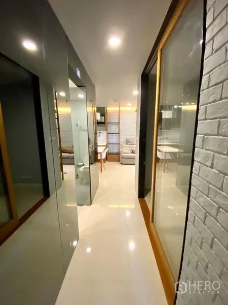Condominium for rent in Chatuchak, Bangkok - Hallway with glossy floor tiles, mirrored doors and a white brick accent wall.