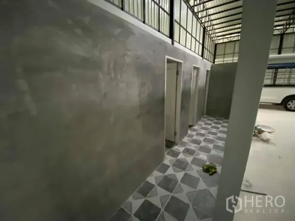 Warehouse for rent in Saphan Sung, Bangkok - Utility corridor with concrete walls, doorways to rooms and patterned floor tiles inside the warehouse.