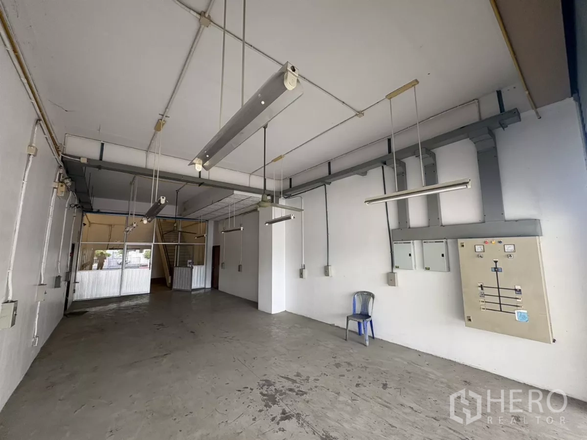 Warehouse for rent in Bang Phli, Samut Prakan - Ground-floor warehouse area with hanging fluorescent lights and electrical panels.